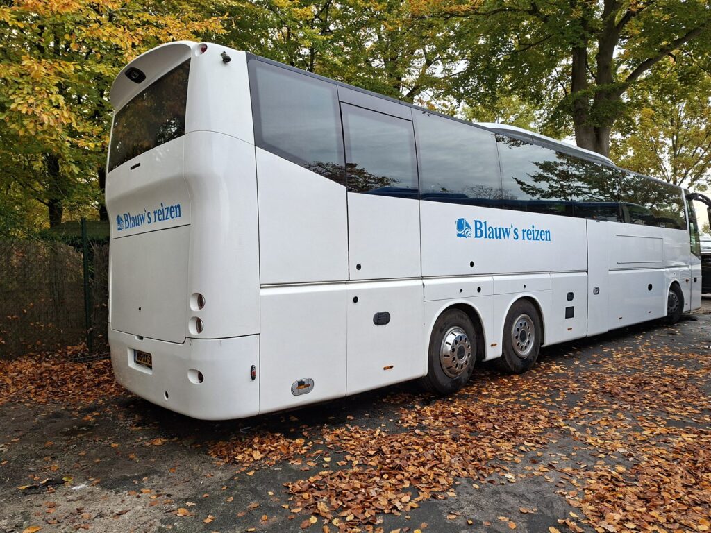 Witte touringcar met de naam van het reisbedrijf op de zijkant