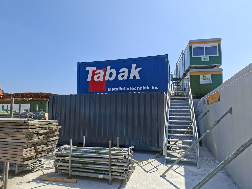 Zeecontainer op een bouwplaats met het logo van Tabak Installatietechniek