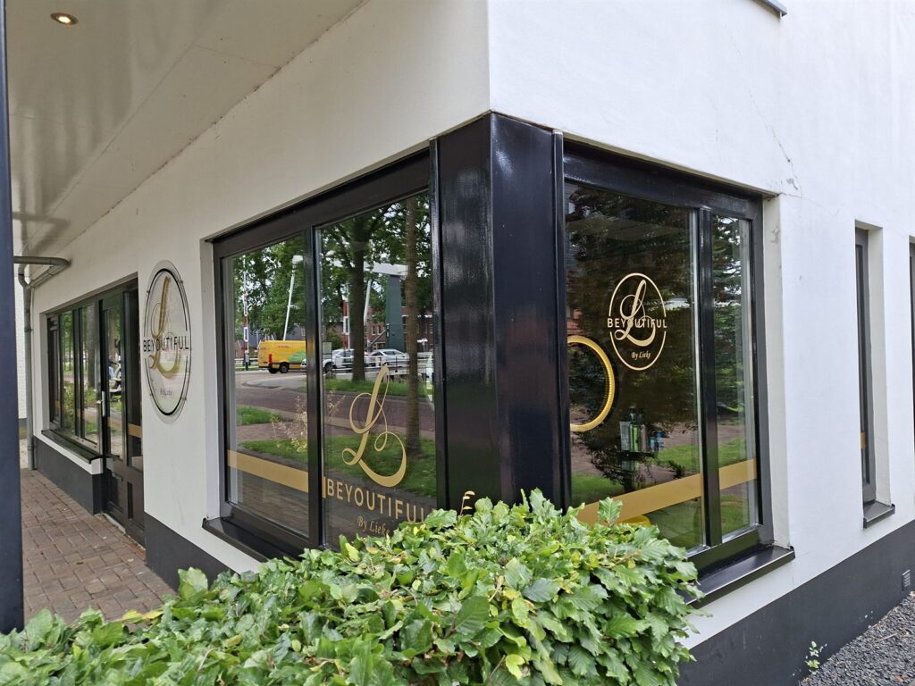 Etalageruit van een salon met het logo in goudkleurige folie