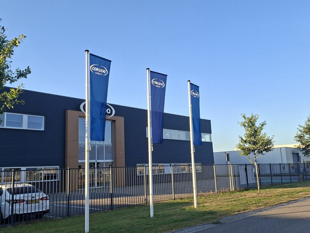 Drie blauwe bedrijfsvlaggen aan masten voor een bedrijfspand